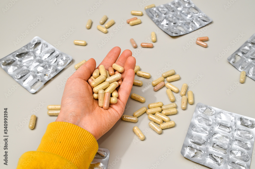 Obraz premium Hands with pharmaceuticals antibiotics pills medicine. colorful antibacterials pills on beige background. capsule pill medicine. Simbol of 2020 year, cronavirus broblem