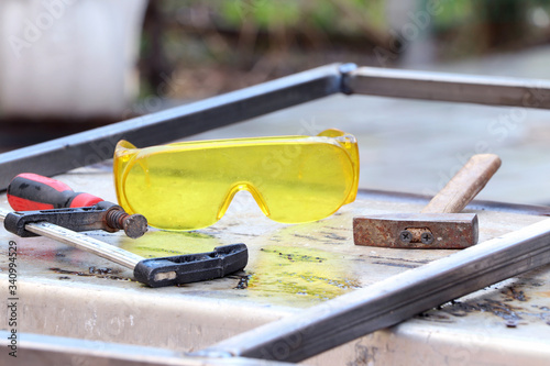 Welding work. Metal profile, safe glasses, hammer and clamp on a metal table. Tools for electro welding. Hand tools. photo