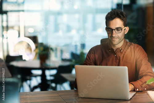 Fotografiet Businessman using a laptop while working late in his office