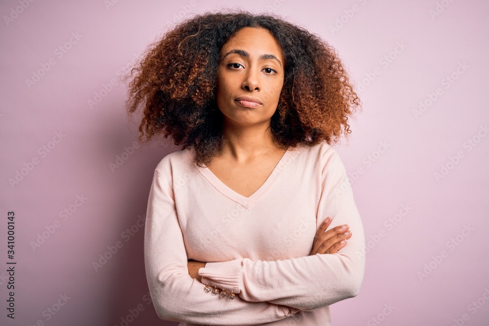 Young african american woman with afro hair wearing casual sweater over pink background Relaxed with serious expression on face. Simple and natural looking at the camera. Young african american woman with afro hair wearing casual sweater over pink background Relaxed with serious expression on face. Simple and natural looking at the camera.