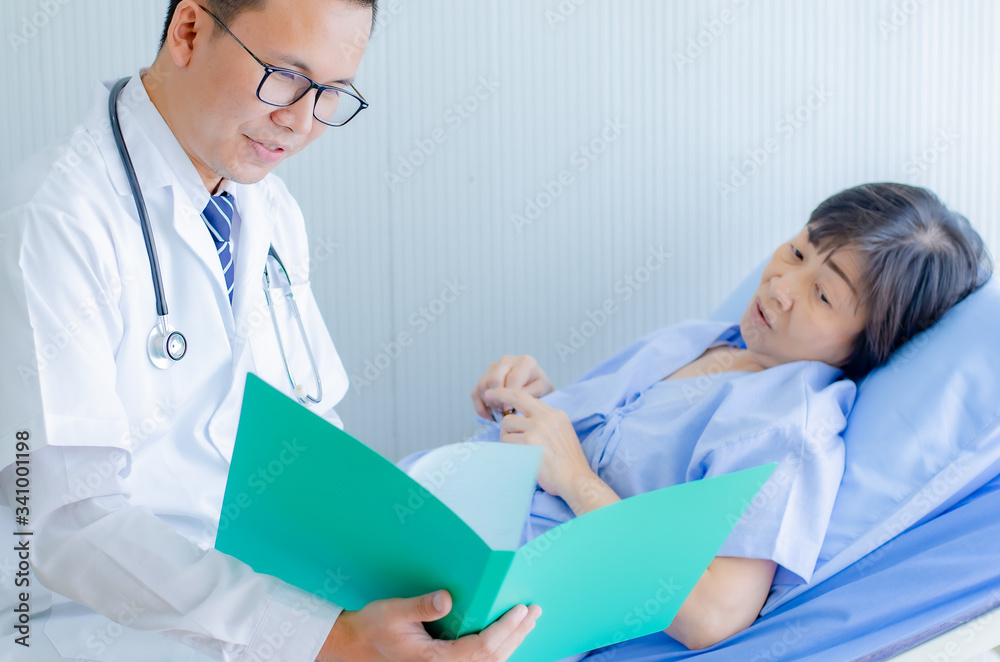 doctor explains examination results and methods of treating disease, determines the surgery date. Let the old woman lying on bed in hospital doctor explains examination results and methods of treating disease, determines the surgery date. Let the old woman lying on bed in hospital