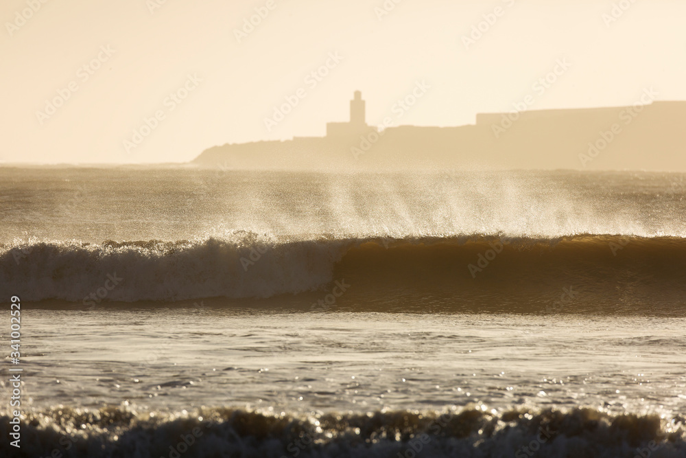Big waves of ocean in Essaouira with Mosque in background. Morocco