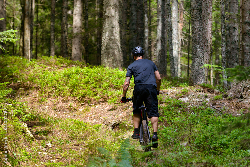Male cyclist with mountainbike up in forest Male cyclist with mountainbike up in forest