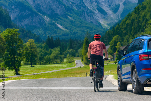 Fototapeta Naklejka Na Ścianę i Meble -  Traveling cyclist on road and car in the valley