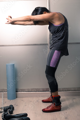 A brunette woman in a fitness uniform is engaged in fitness at home.