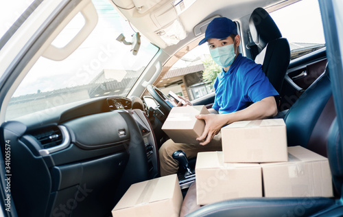 Asian Delivery man wearing mask send a package holding smartphone on front home receiver shipping deliver cargo social distancing, Many parcel in hatchback car while the virus is spreading medical.