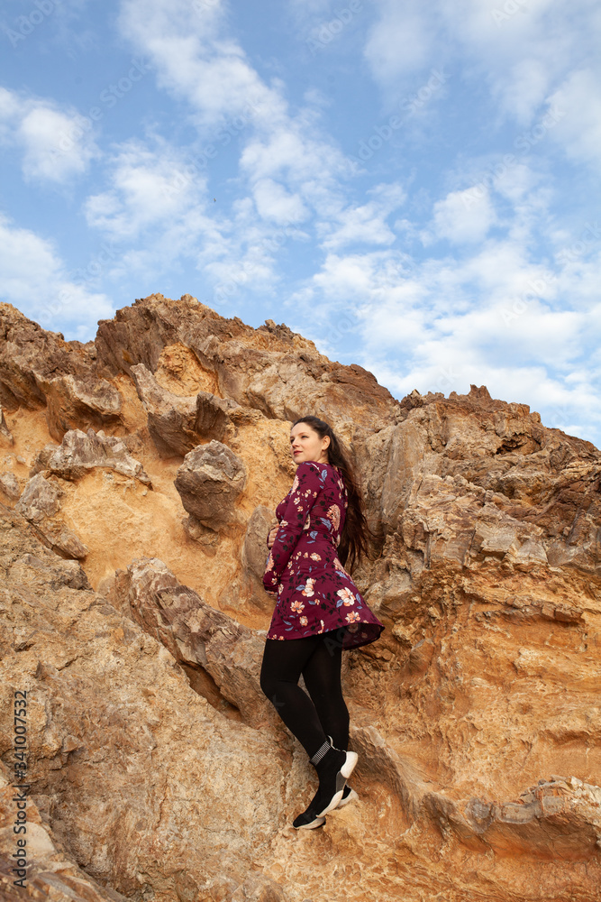 portrait of a beautiful expectant girl with long hair on a background of sea and rock, outdoor, Active pregnancy in nature