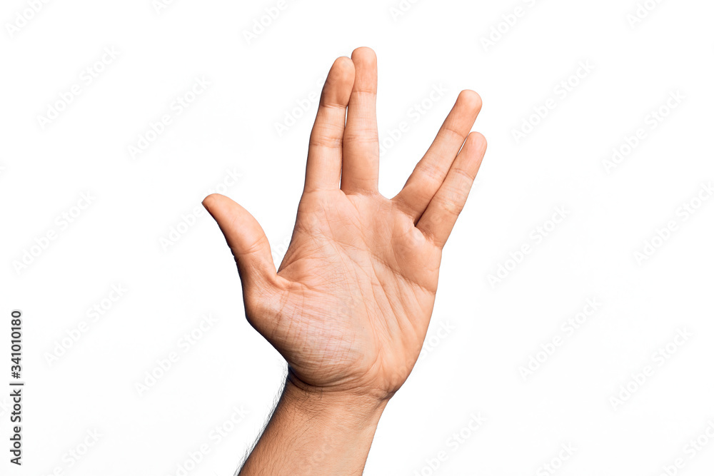 Hand of caucasian young man showing fingers over isolated white background greeting doing Vulcan salute, showing hand palm and fingers, freak culture Hand of caucasian young man showing fingers over isolated white background greeting doing Vulcan salute, showing hand palm and fingers, freak culture