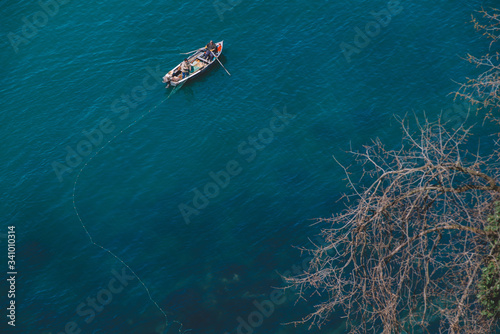 Net Fishing scene into the blue sea with fisherman and a little boat.