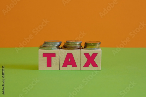 Rows of coin stacks with toy blocks symbolizing taxation.