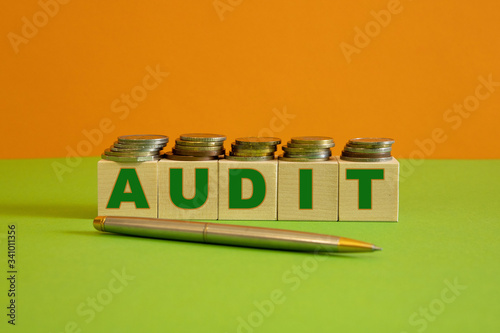 A metal handle and rows of coin stacks with toy wooden blocks symbolizing a financial audit. Space for additional text.