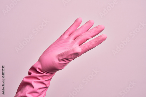 Hand of caucasian young man with cleaning glove over isolated pink background presenting with open palm, reaching for support and help, assistance gesture