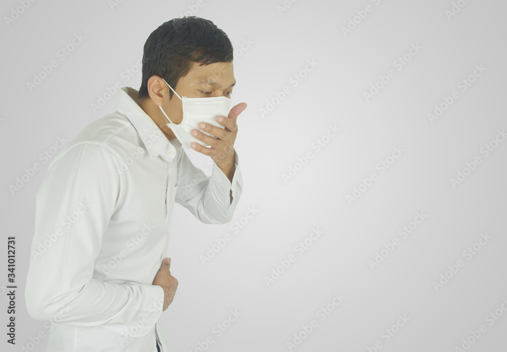 Side view of sick man coughing while wearing a medical mask on grey background. Side view of sick man coughing while wearing a medical mask on grey background.