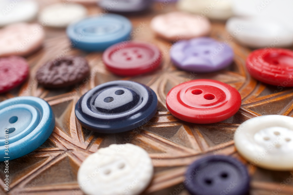 Multicolored buttons on wooden background with arnament Multicolored buttons on wooden background with arnament