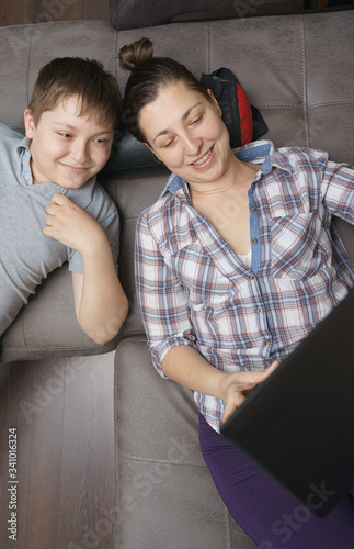 Mother and her children are talking online by notebook with relatives or friends. Online call friends, grandparents. Family in quarantine stay at home in self isolation.