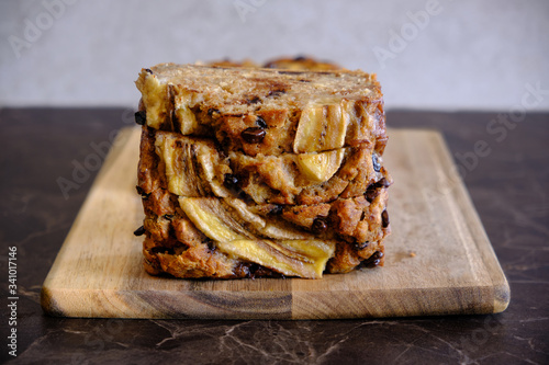 Stack of moist homemade banana bread slices on wooden board, rustic healthy breakfast dessert