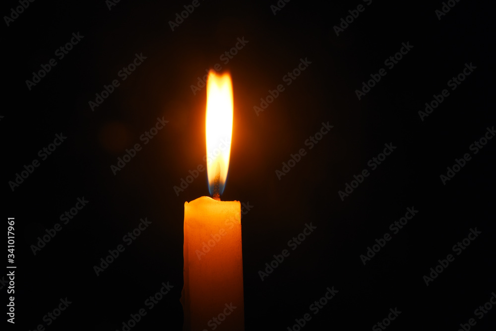 Lit flame of a candle on dark background Lit flame of a candle on dark background