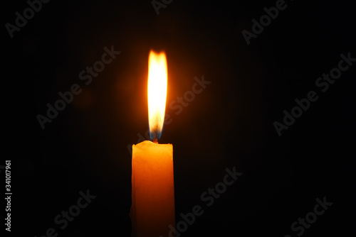 Lit flame of a candle on dark background 