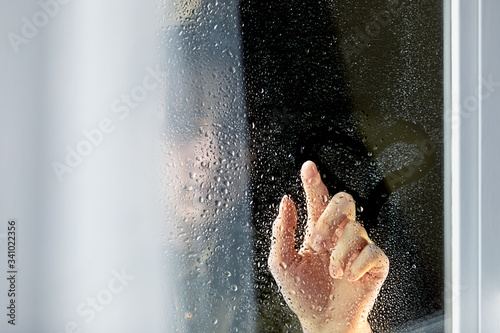 The girl s hand draws a symbol of love-a heart-on the window glass with drops. The concept of romantic  love during war  waiting for peace.