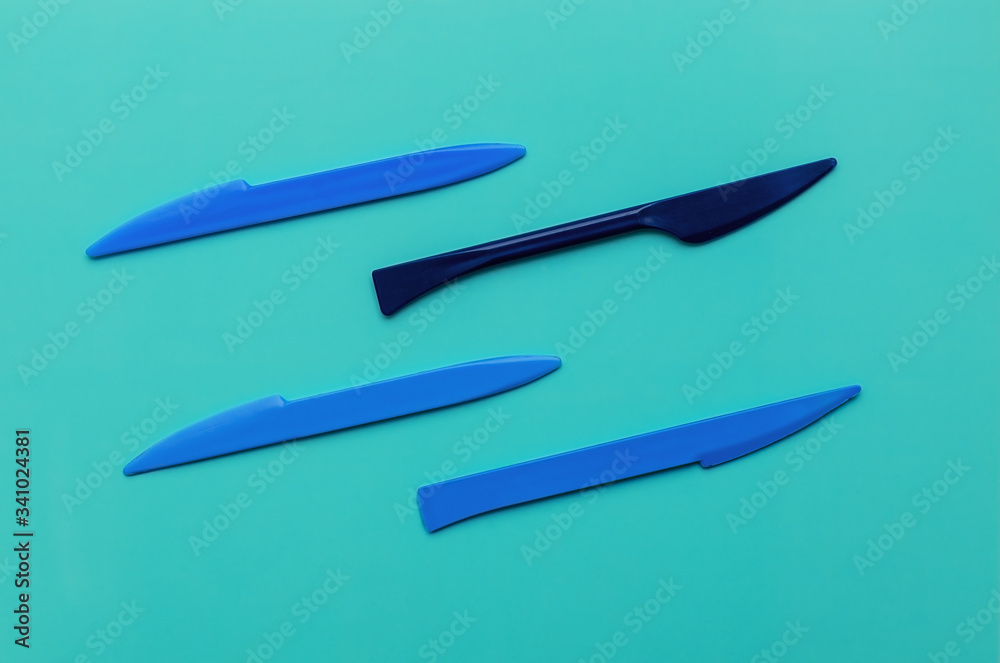 Obraz premium Blue plasticine knives for cutting plasticine on a mint background. Flat lay, copy space, top view. Hobby.