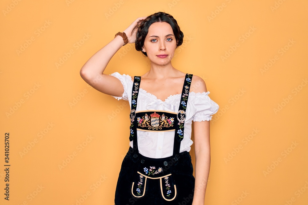 Young beautiful german woman with blue eyes wearing traditional octoberfest dress confuse and wonder about question. Uncertain with doubt, thinking with hand on head. Pensive concept. Young beautiful german woman with blue eyes wearing traditional octoberfest dress confuse and wonder about question. Uncertain with doubt, thinking with hand on head. Pensive concept.