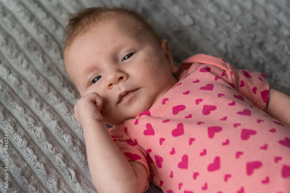 A small newborn girl looks thoughtfully at the camera A small newborn girl looks thoughtfully at the camera