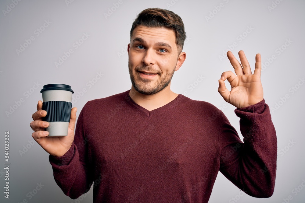 Young man with blue eyes drinking coffee from take away plastic bottle over isolated background doing ok sign with fingers, excellent symbol Young man with blue eyes drinking coffee from take away plastic bottle over isolated background doing ok sign with fingers, excellent symbol