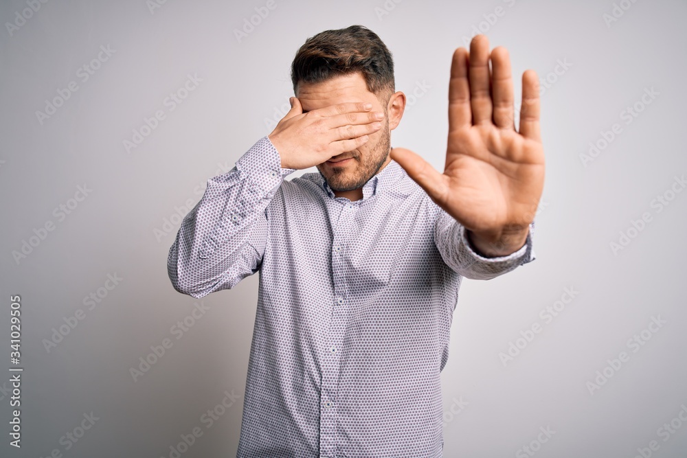 Young business man with blue eyes standing over isolated background covering eyes with hands and doing stop gesture with sad and fear expression. Embarrassed and negative concept. Young business man with blue eyes standing over isolated background covering eyes with hands and doing stop gesture with sad and fear expression. Embarrassed and negative concept.