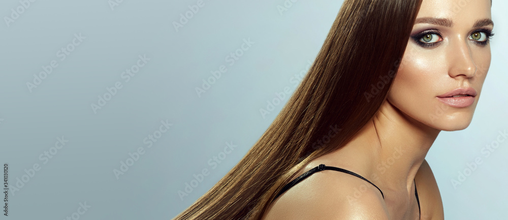 Φωτογραφία A young, beautiful, well-groomed girl with bright makeup and smooth, silky, long dark hair posing in the studio on a light background