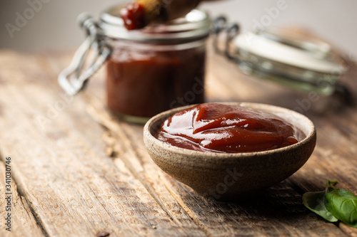 Barbecue sauce in a saucer with basting brush over rustic barn wood table with copy space.