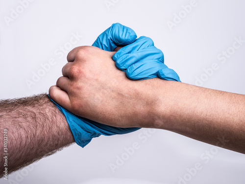 Dramatic grasp with a blue medical glove and a bruised and dirty woman's hand. Concept showing appreciation to medical professionals for their hard work. Profile view on white background.
