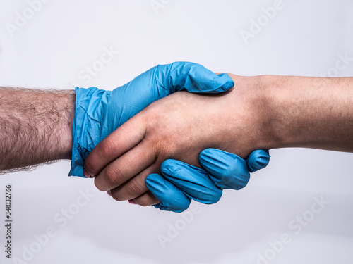 Dramatic handshake with a blue medical glove and a bruised and dirty woman's hand, profile view on white background.