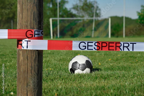 A soccer field is closed with a barrier tape. Due to the Corona pandemic, soccer matches have been cancelled. German text means: closed. photo