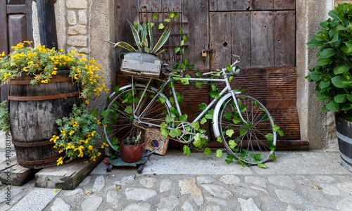 Old and decorative bicycle leaning against old wooden door at traditional village in Spain