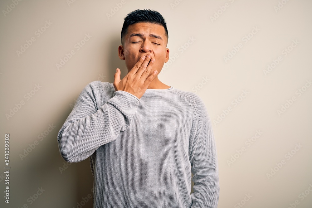 Young handsome latin man wearing casual sweater standing over isolated white background bored yawning tired covering mouth with hand. Restless and sleepiness. Young handsome latin man wearing casual sweater standing over isolated white background bored yawning tired covering mouth with hand. Restless and sleepiness.