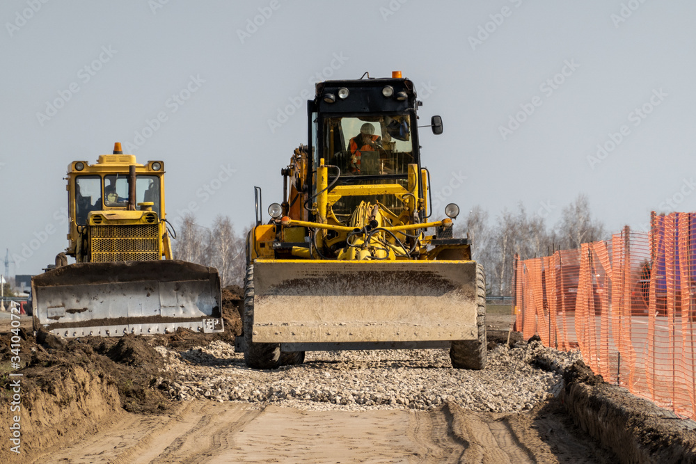 Road repairs. Expansion of the roadbed. Graders level the rubble layer. Selective focus. Road repairs. Expansion of the roadbed. Graders level the rubble layer. Selective focus.
