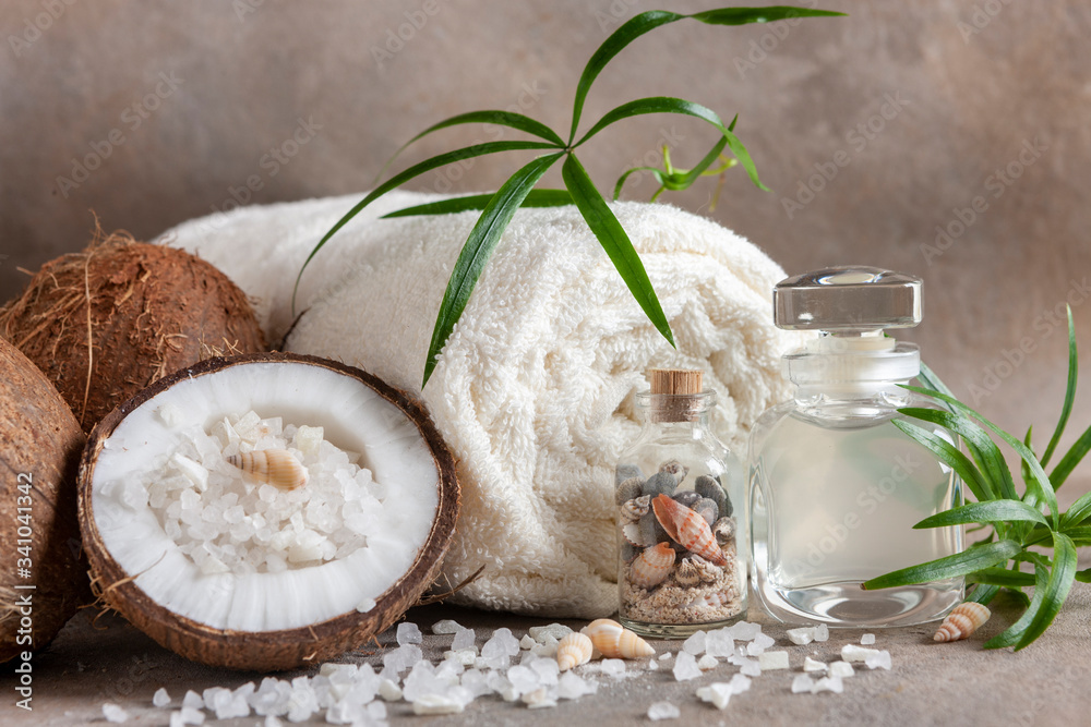 Close-up of Coconut, soft towels, coconut essence, sea salt, shells and tropical greens. Spa concept, beauty and health salon, cosmetics store. Close-up of Coconut, soft towels, coconut essence, sea salt, shells and tropical greens. Spa concept, beauty and health salon, cosmetics store.