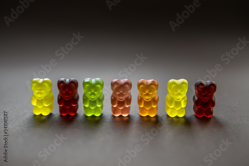 Collection of backlit multicolored gummy bears on a neutral background. Shallow depth of field. photo