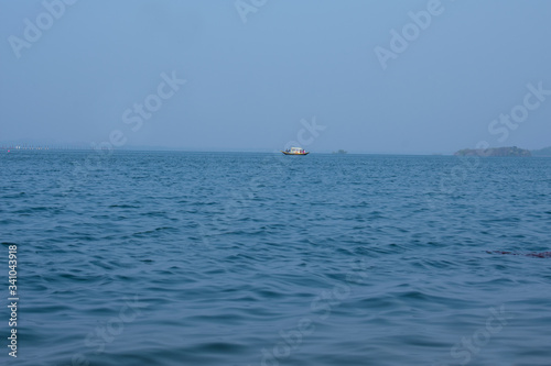 a beautiful blue lake with small waves flowing with a boat in the far