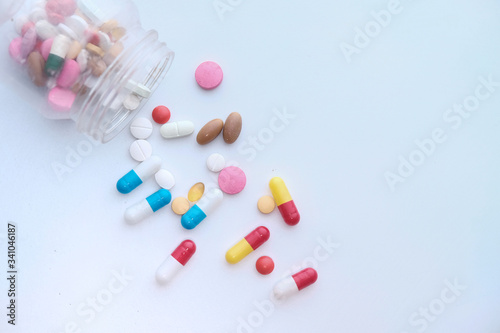 pills spilling from a container on white background 