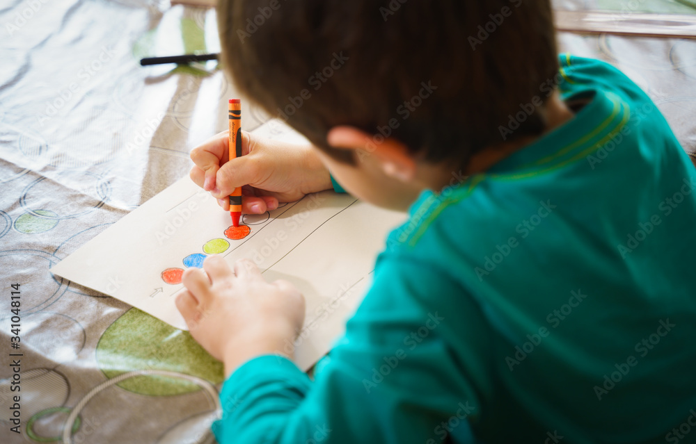 child drawing with crayons on paper or doing homework from home. Home schooling or e-learning concept child drawing with crayons on paper or doing homework from home. Home schooling or e-learning concept