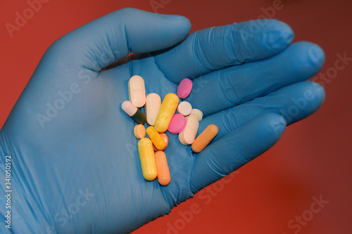 pills in the palm of a doctor's blue glove.
