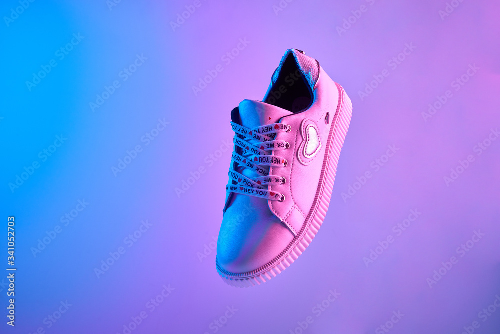 Trendy white teenage sneaker flying in trendy neon light. Levitation Shoe in red, blue light. Creative minimalism. - obrazy, fototapety, plakaty 