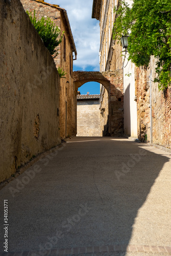 a narrow street with an arch on a sunny summer day in Tuscany, Italy