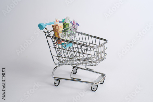 Shopping cart with 100 €, 50 €, 500 euro bills. On white background with copy space