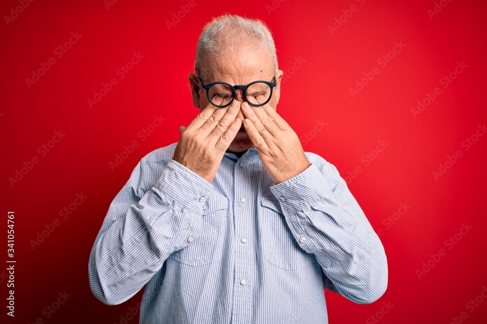 Middle age handsome hoary man wearing casual striped shirt and glasses over red background rubbing eyes for fatigue and headache, sleepy and tired expression. Vision problem Middle age handsome hoary man wearing casual striped shirt and glasses over red background rubbing eyes for fatigue and headache, sleepy and tired expression. Vision problem