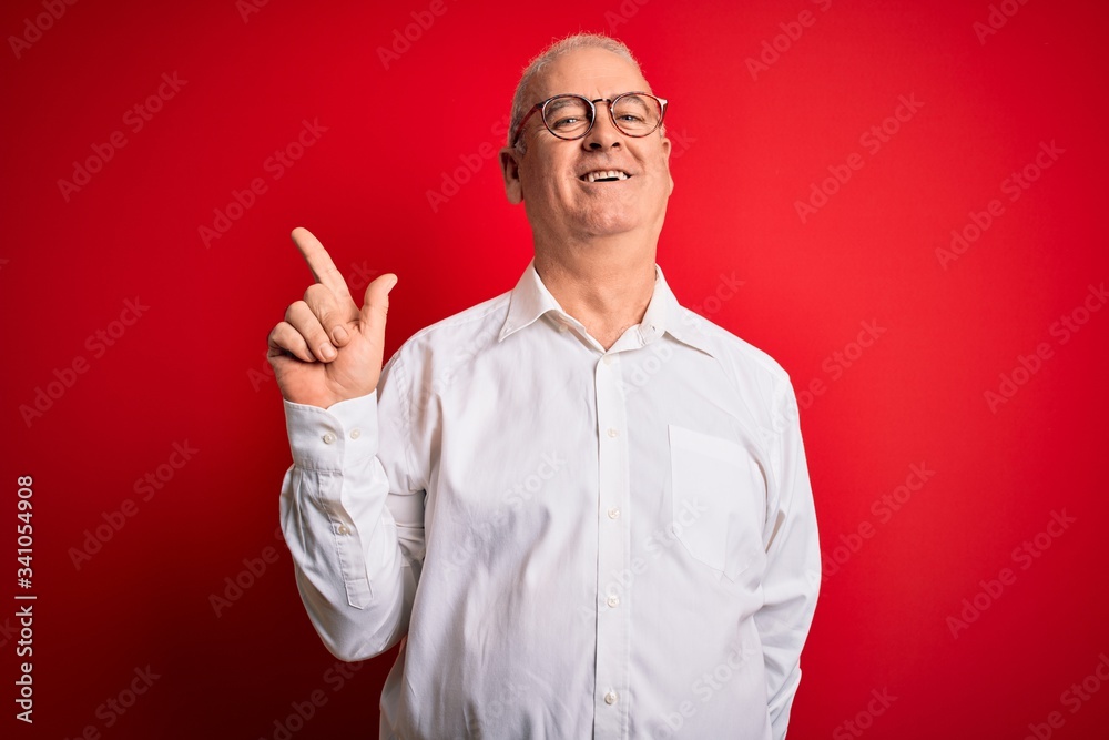 Fototapeta premium Middle age handsome hoary man wearing casual shirt and glasses over red background with a big smile on face, pointing with hand finger to the side looking at the camera.