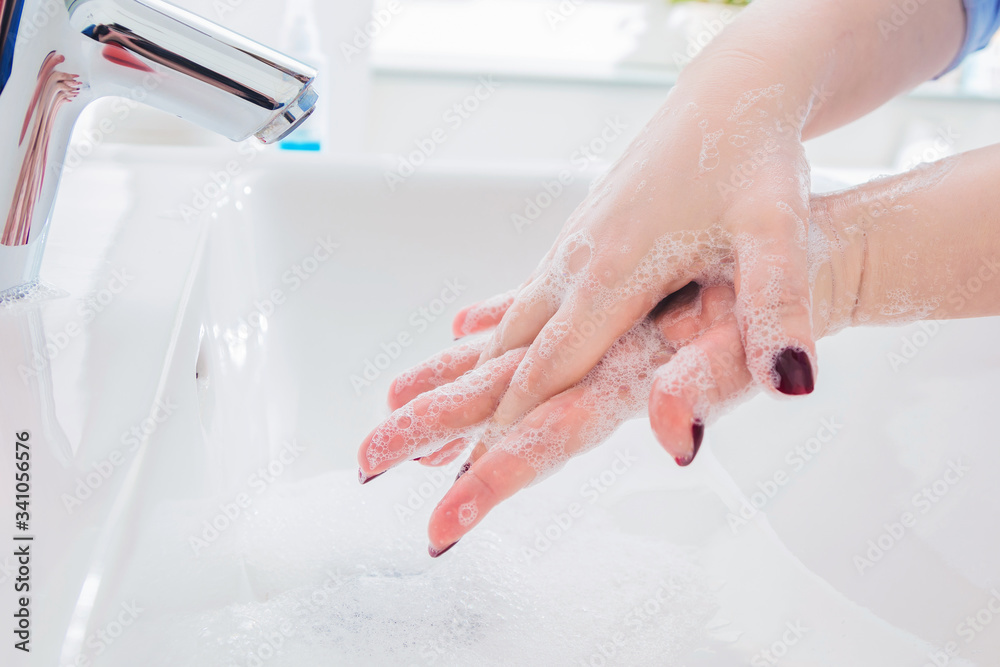 Fototapeta premium Frau benutzen Seife um Händewaschen unter dem Wasserhahn. Hygienekonzept Hand Detail.cor