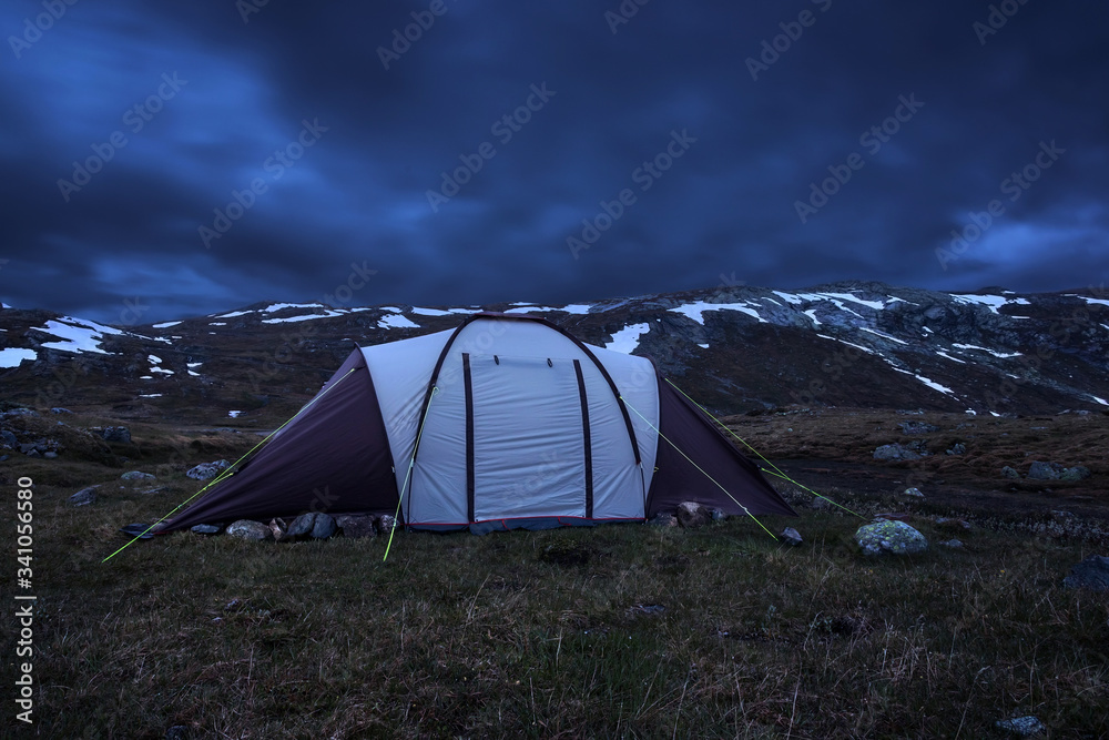 Big tent on the background of mountains with snow, night, spring in the Norwegian mountains