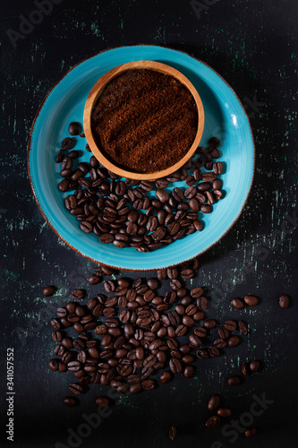 Wooden bowl with coffee powder and ceramic bowl with roasted coffee beans. all in black background